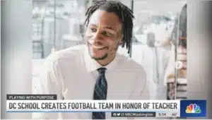 In a still from an NBC4 news article, Keenan Anderson, an attractive young black man, smiles in his classroom.